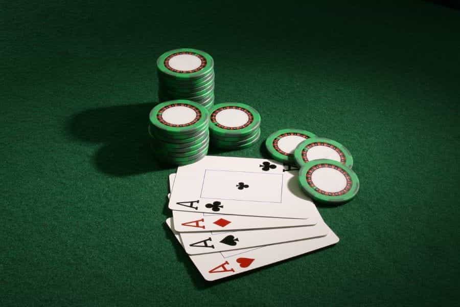 Four Aces cards lie on poker table beside chips.