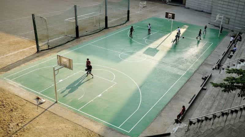 A small group of men playing basketball on an outdoor court.