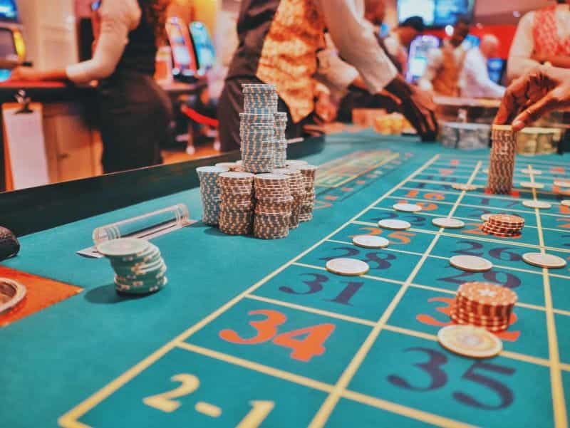 A casino table with numbers on it and piles of chips on different numbers.