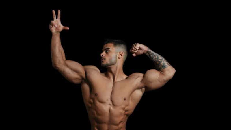 A topless male bodybuilder flexes.