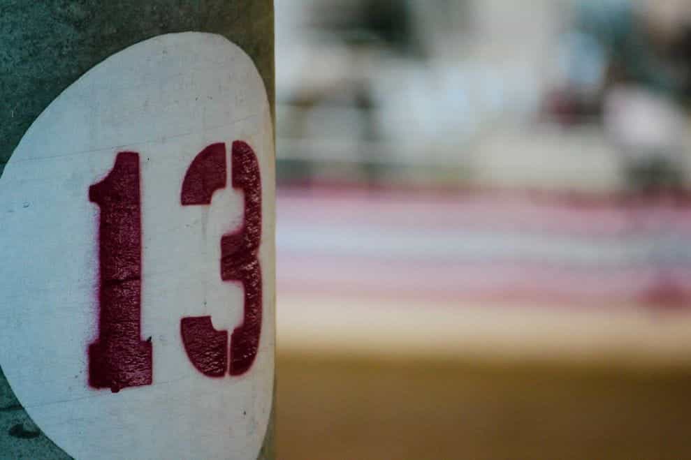 The number 13 is spray painted in red with a stencil on a grey pole.