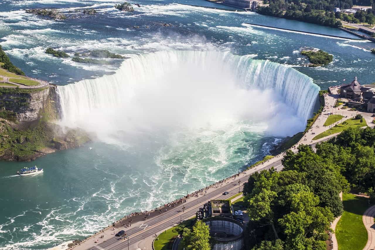 The iconic Niagara Falls waterfall on the border of New York state and the Canadian province of Ontario, with throngs of sightseers on the boardwalk around the landmark.