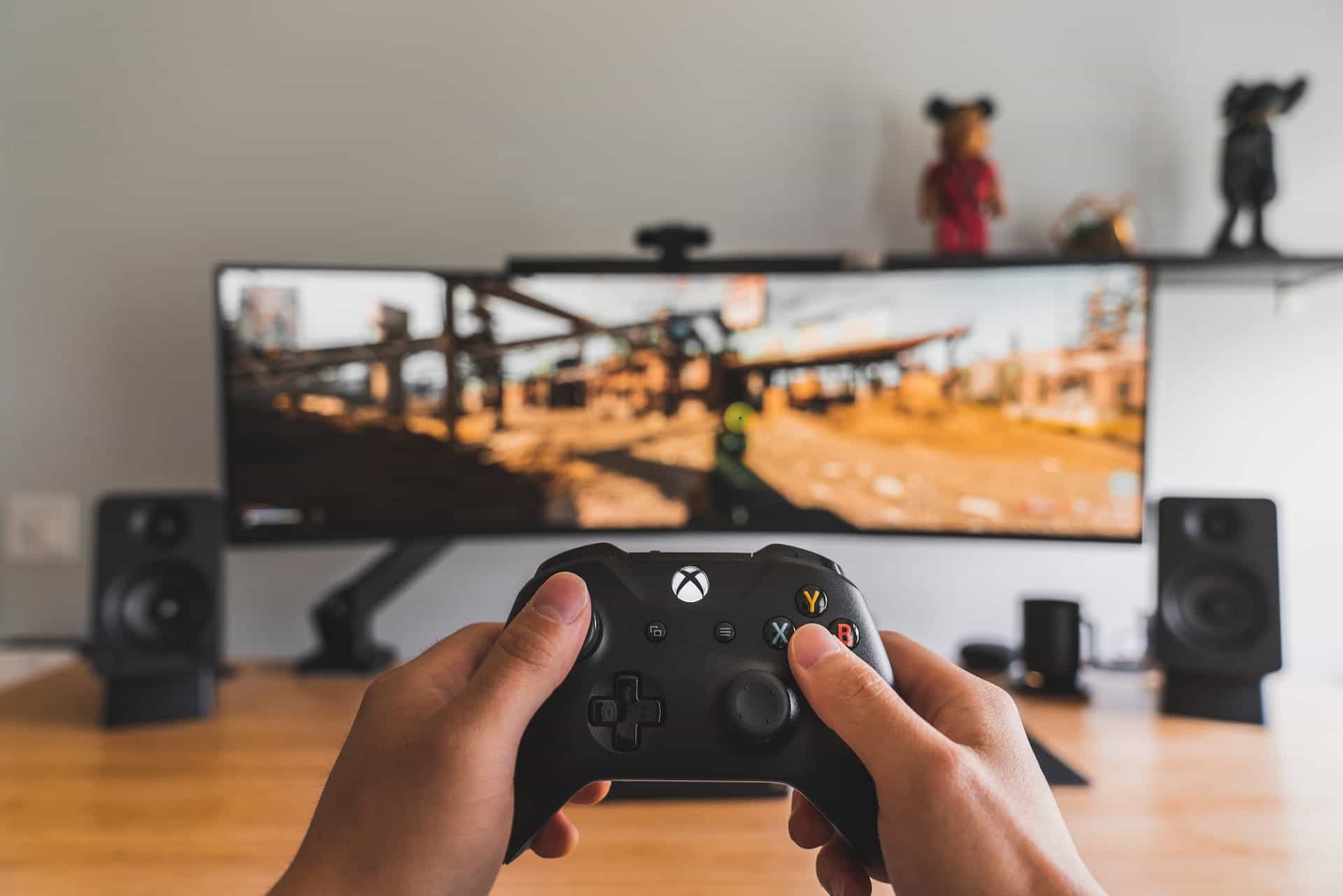 Hands on a video game controller in front of a TV where an action game is being played.