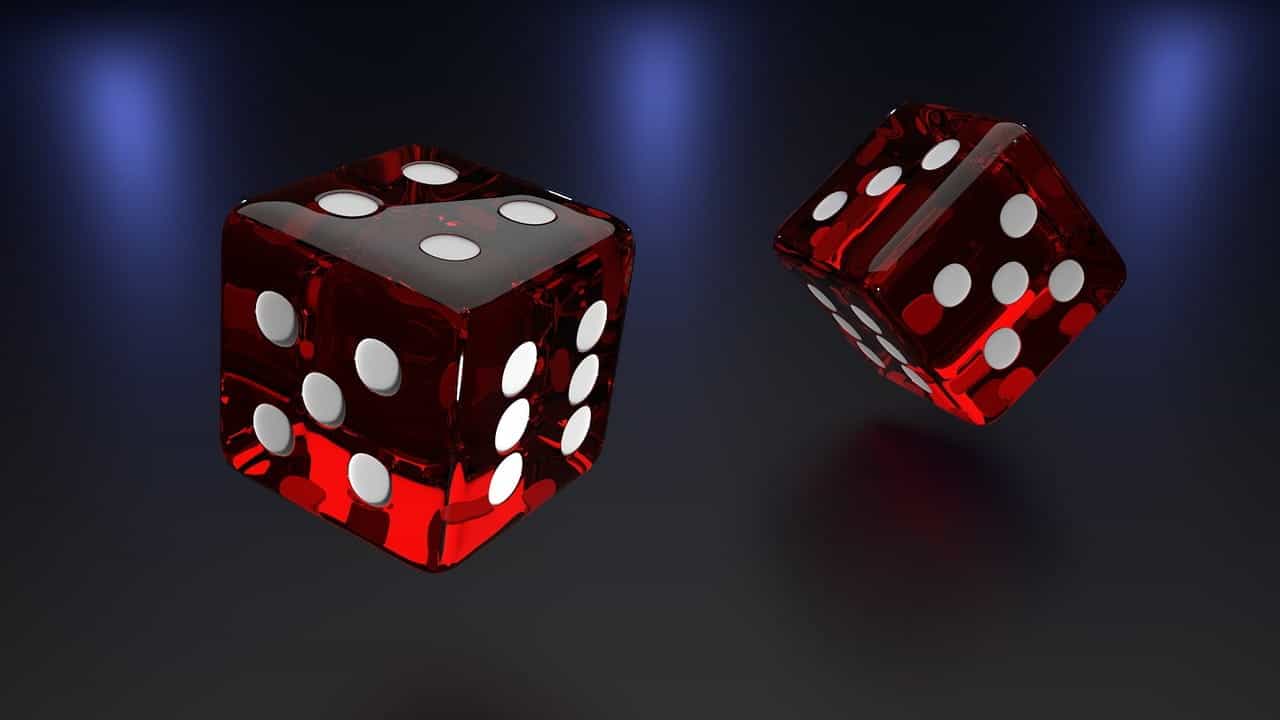 A pair of shiny and translucent red die flying through the air on a dark gradient background.