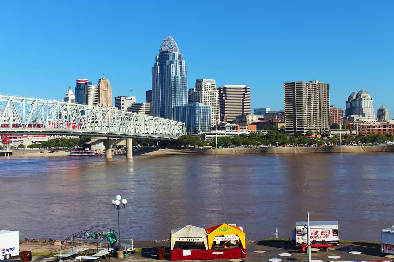 A large suspension bridge going over the Ohio River from the state of Ohio into Kentucky, with the tall buildings and skyscrapers of Cincinnati seen on the other side of the river.