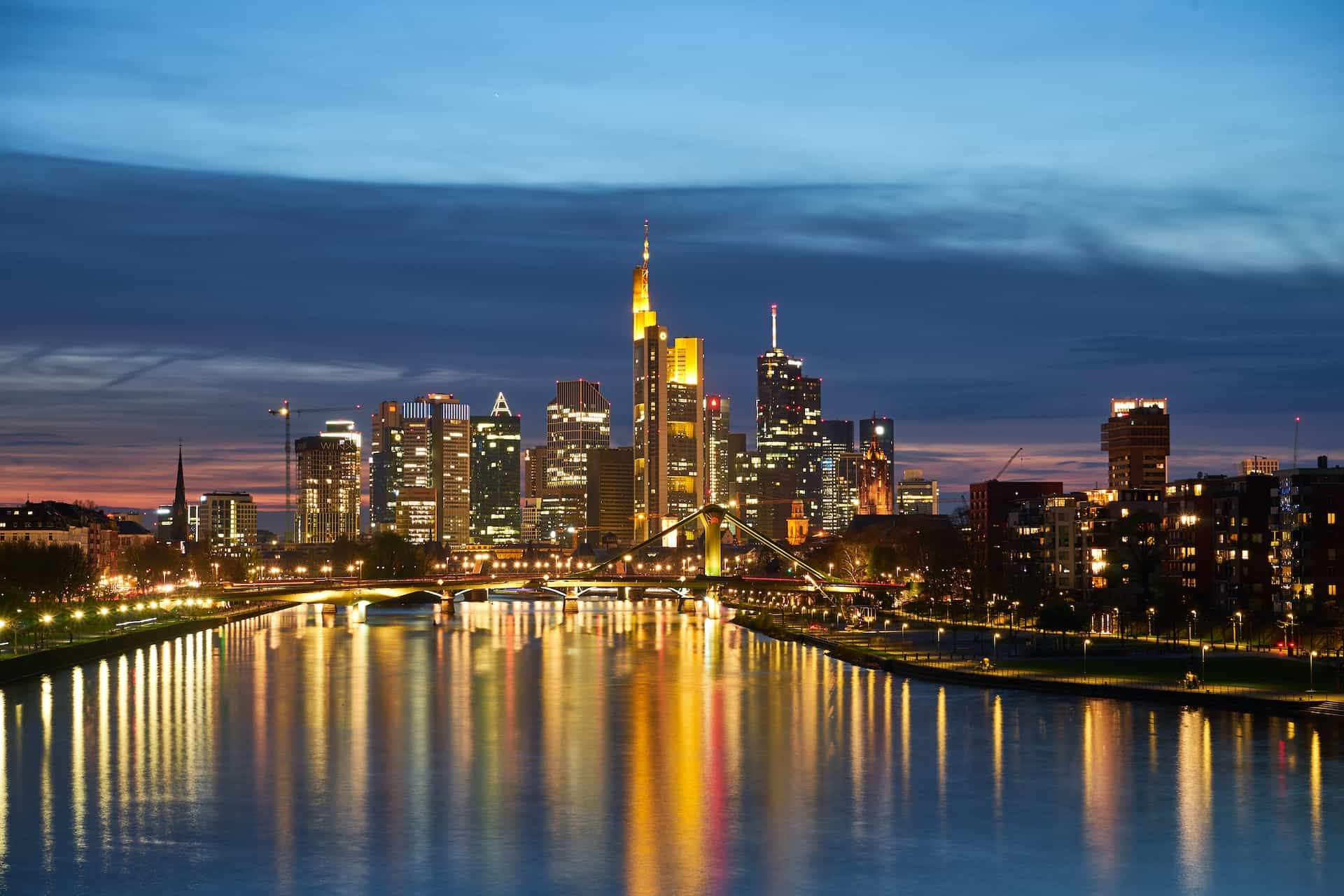 A well-lit city near a river in the evening.