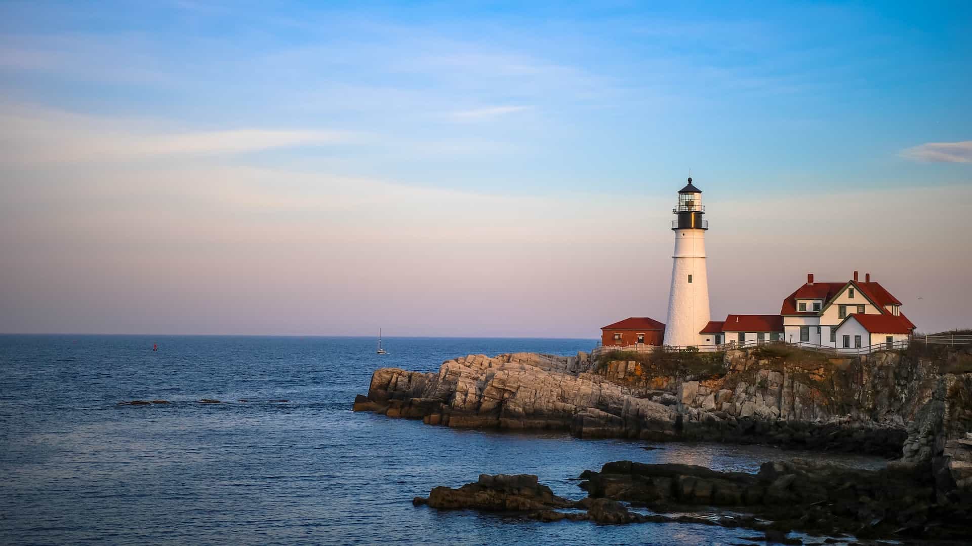 A typical New England lighthouse next to another set of buildings at Cape Elizabeth in the northeastern state of Maine, with the great Atlantic Ocean extending out beyond.